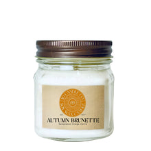 Load image into Gallery viewer, 
A autumn brunette scented wax candle in a clear glass 8 oz mason jar with a dark brown metal lid and a tan paper label. The label features a circular orange logo for JD CANDLE CO. SOY WAX CANDLE
