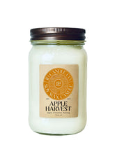 Load image into Gallery viewer, An Apple Harvest scented wax candle in a clear glass 16 oz mason jar with a dark brown metal lid and a tan paper label. The label features a circular orange logo for JD CANDLE CO. SOY WAX CANDLE