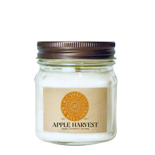 Load image into Gallery viewer, An Apple Harvest scented wax candle in a clear glass 8 oz mason jar with a dark brown metal lid and a tan paper label. The label features a circular orange logo for JD CANDLE CO. SOY WAX CANDLE