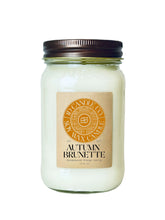 Load image into Gallery viewer, 
A autumn brunette scented wax candle in a clear glass 16 oz mason jar with a dark brown metal lid and a tan paper label. The label features a circular orange logo for JD CANDLE CO. SOY WAX CANDLE
